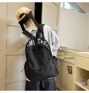 Close-up of black canvas backpack with white ZIZI lettering and orange side label