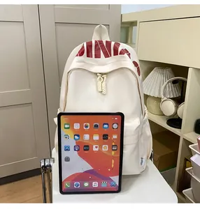 Detail of ivory white backpack showing large capacity next to a tablet for size reference