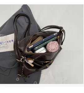 Vista detallada del espacioso interior de un bolso bandolera de cuero PU marrón oscuro y metal