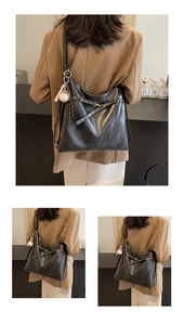 Detalle del bolso tote de cuero sintético negro con colgante de béisbol y hebilla decorativa