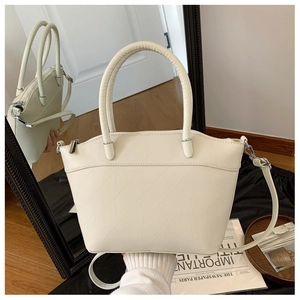 Close-up of cream bucket bag showing geometric quilted texture and silver zipper detail