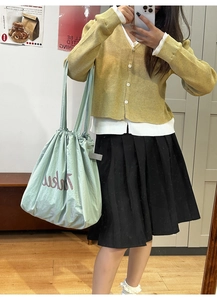 Mint green nylon drawstring tote bag shown in a mirror selfie for outfit styling