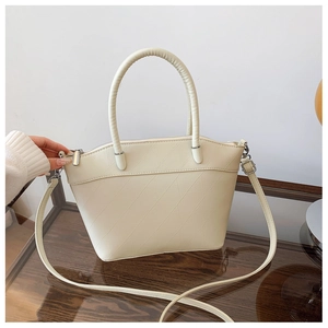 Close-up of cream-colored bucket bag featuring a unique crackle texture and round handle