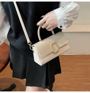 Detail of beige leather crossbody bag featuring lychee texture and gold metal buckle
