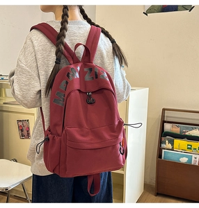 Close-up of burgundy large-capacity backpack with letter print and dual zipper compartments
