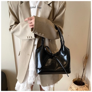 Detail of glossy black oil wax leather tote bag with a chic bow decoration for women