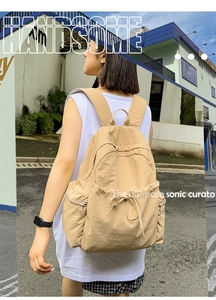 Outdoor shot of light brown nylon backpack with side pockets and drawstring closure