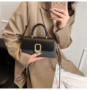 Detail of elegant two-tone crossbody bag with gold buckle on a stylish model
