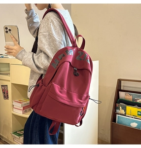 Close-up of a deep red canvas backpack featuring black MRM ZI lettering and side drawstrings