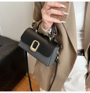 Detail of elegant two-tone handbag with gold metal buckle and textured woven fabric