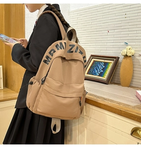 Brown canvas casual backpack worn by a model in a cozy indoor setting with large front pocket