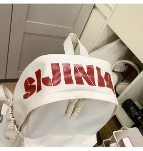 Close-up of SIJINIA red letter print on white synthetic leather backpack with woven zipper pull