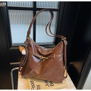 Detalle del bolso tote de cuero marrón vintage con hebillas metálicas y colgante
