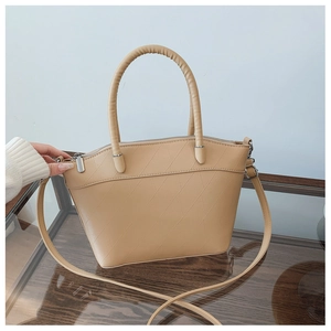 Close-up of beige leather bucket bag with diagonal diamond quilted pattern and silver metal zip