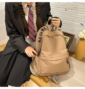 Detail of khaki canvas backpack with MRMI ZI lettering and front zipper pocket