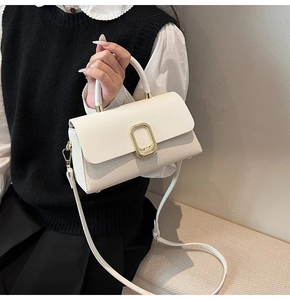 Detail showing the woven texture and golden square lock of the white leather handbag