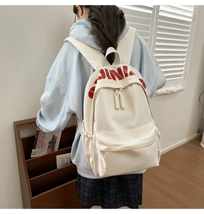 Detail of white nylon backpack with red China lettering and woven rope zipper pull