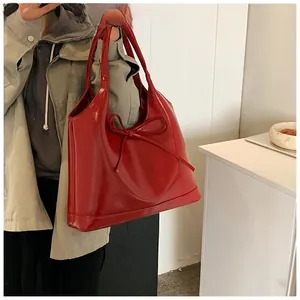 Close-up of a large red oil wax leather tote bag featuring a decorative oversized bow detail