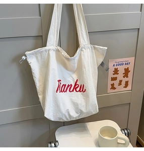 Detailed view of white nylon tote bag with red Tianku text and side drawstring detail
