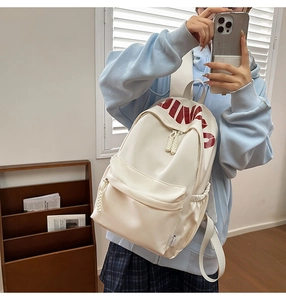 Close-up of white campus backpack with red JINGO print and functional front flap pocket