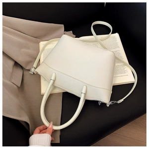 Detail showing the cream bucket bag's geometric embossed pattern and silver hardware
