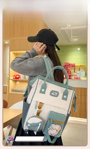 Détail d'un sac à dos en toile beige et vert avec broderie et porte-monnaie