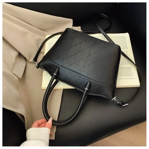 Detailed macro view of diamond quilted black PU leather bucket bag with silver metal hardware