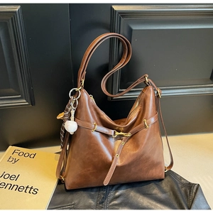 Detalle de bolso hobo vintage marrón con colgante de béisbol y hebilla fina