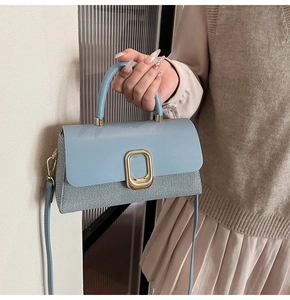 Detail of blue leather and textured fabric patchwork handbag with golden metal buckle