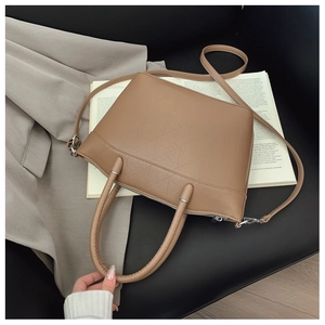 Close-up of khaki bucket bag with geometric stitching, silver hardware, and dual handles