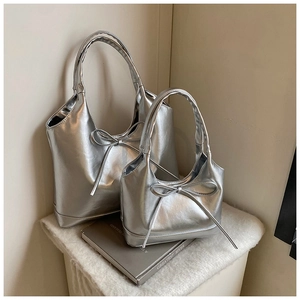 Detail of silver metallic tote bag with oil wax texture and delicate ribbon bow accessory