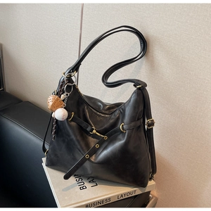 Detalle de bolso tote de cuero PU negro con herrajes dorados y llavero de guante béisbol