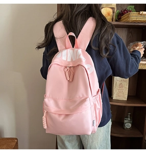 Close-up of pink fashion backpack with white PINK lettering and woven zipper puller