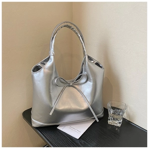 Detailed close-up of a metallic silver tote bag with a stylish ribbon bow ornament