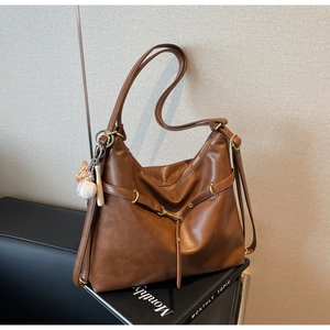 Detalle de bolso tote vintage marrón con hebilla de metal retro y colgante de béisbol