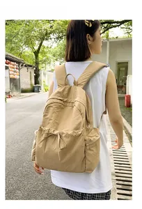 Detail view of khaki nylon backpack featuring drawstring front pocket and durable texture