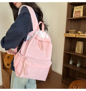 Detailed view of pink backpack side pocket and woven zipper pulls on nylon fabric