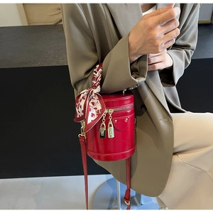 Detail of red cylindrical vanity bag featuring gold padlocks and silk scarf handle