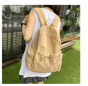Close-up of khaki school backpack with a stylish drawstring bow and water-resistant nylon