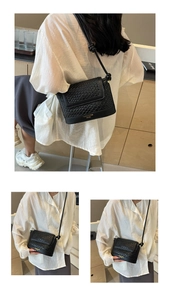Détail de la texture tressée du sac seau noir avec logo doré et bandoulière à nœud