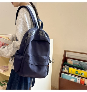 Detail view of the deep blue casual backpack featuring side elastic pocket and letter print