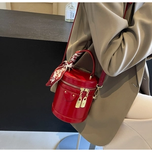 Détail du sac seau cylindrique rouge avec fermoirs dorés et foulard en soie imprimé