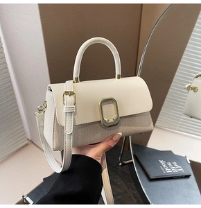 Detail of elegant cream handbag with woven leather texture and gold metal clasp