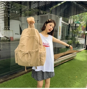 Outdoor shot of a light khaki large capacity nylon backpack with drawstring front pocket