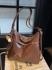 Bolso hobo vintage de cuero marrón oscuro con colgante de béisbol sobre mármol