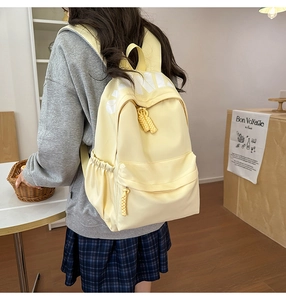 Detail of light yellow casual backpack with white letter print and woven rope zipper pull