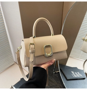Detail of beige flap square bag featuring woven texture and gold metal buckle finish