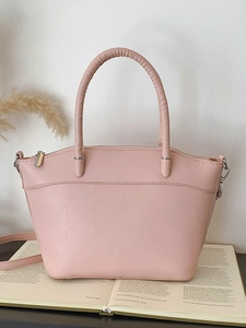 Minimalist pink bucket bag with geometric texture on a black desk with books