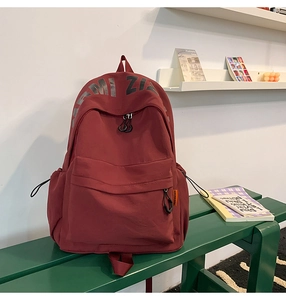 Detailed macro view of deep red durable nylon backpack with side pockets and main zippers