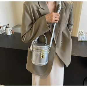 Detail view of silver cylindrical bucket bag with silk scarf and gold lock zipper